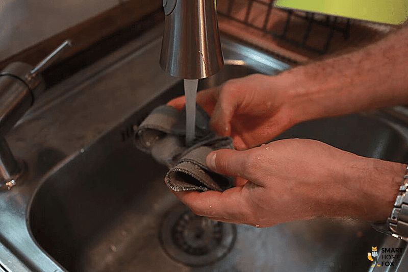 Das Wischpad des WINBOT W1 PRO wird unter fließendem Wasser angefeuchtet